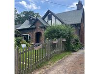 Charming brick home featuring a well-maintained lawn, picket fence with flowers, and an inviting arched entryway at 451 S Columbia Dr, Decatur, GA 30030