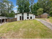 Charming home featuring a lush front yard, long driveway, and inviting curb appeal surrounded by mature trees at 2123 Drew Valley Ne Rd, Brookhaven, GA 30319