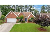 Charming red brick home with a well-manicured lawn, a two-car garage, and a welcoming blue front door at 4434 Austin Hills Dr, Suwanee, GA 30024