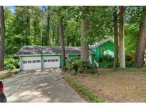 Charming green two-car garage home nestled among mature trees offering natural light and privacy at 5760 Windermere Ct, Lithonia, GA 30038