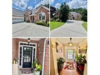 Red brick home featuring an attached garage, a black front door, and manicured landscaping at 1902 Commons View Cir, Snellville, GA 30078