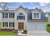 Charming two-story home featuring a well-manicured lawn, attached two-car garage, and solar panels on the roof at 4092 Arabian Way, Snellville, GA 30039