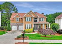 Charming two-story home with a manicured lawn, mature trees, and a two-car garage, creating a welcoming curb appeal at 1346 Wind Chime Ct, Lawrenceville, GA 30045