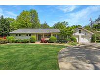 Charming single-Gathering home featuring well-manicured lawn, mature trees, and two-car garage at 3005 Howell Mill Rd, Atlanta, GA 30327