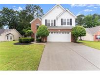 Charming two-story home featuring a brick and white exterior, landscaped yard, and an extended driveway at 1980 Heatherton Rd, Dacula, GA 30019
