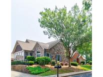 Charming stone and brick home featuring manicured landscaping, complemented by a lush tree and a convenient mailbox at 4347 Lanier Ridge Walk # 1501, Cumming, GA 30041