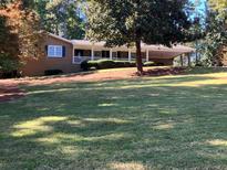 Charming single-story brick home with a long front porch, mature trees, and a large, well-maintained front yard at 840 Hickory Sw Dr, Marietta, GA 30064