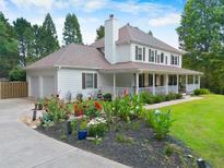 Charming two-story home featuring a welcoming front porch, well-manicured lawn, and vibrant flower beds at 2820 Channing Way, Cumming, GA 30040