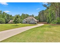 Charming two-story home with a lush green lawn and long driveway at 33 Vinery Ct, Sharpsburg, GA 30277