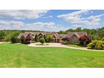 Expansive front lawn and circular driveway leading to a custom home with mature trees at 2220 Peachtree Rd, Cumming, GA 30041
