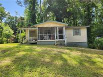 Modest single-story home with screened-in porch and a sloped walkway, set against a backdrop of lush greenery at 53 Elm St, Hampton, GA 30228