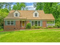 Charming brick home with a lush green lawn, dormer windows, and verdant landscaping at 3449 Parkview Dr, Atlanta, GA 30337