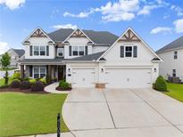 Beautiful two-story home with a three-car garage, manicured lawn, and lovely landscaping at 4105 Woodwind Dr, Cumming, GA 30028