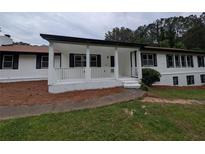 Charming single-story home featuring a covered front porch, white siding, black shutters, and well-maintained landscaping at 871 Cowan Se Rd, Conyers, GA 30094