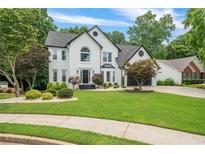 Beautiful two-story home featuring a lush lawn, professional landscaping, and a charming, painted white brick facade at 340 Chandler Ct, Sugar Hill, GA 30518