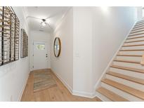 Bright foyer featuring light hardwood floors, white walls, and a staircase leading to the second floor at 436 Carrera Ln, Acworth, GA 30102