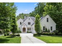 Beautiful two-story white home with lush landscaping, a driveway, and a charming arched wooden front door at 803 Courtenay Ne Dr, Atlanta, GA 30306