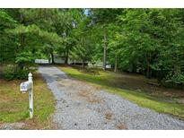 Long gravel driveway leading to a charming home surrounded by lush greenery and a mailbox at the entrance at 6201 Davids Se Way, Acworth, GA 30102