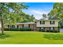 Charming two-story home with a brick and siding facade and a beautifully landscaped front yard under a sunny blue sky at 115 Creek Cir, Stockbridge, GA 30281