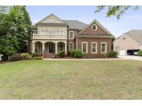 Elegant two-story brick home with a columned front porch and well-manicured lawn and professional landscaping at 1565 Briergate Dr, Duluth, GA 30097