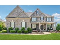 Beautiful two-story brick home with a manicured lawn, flower beds, and a covered front porch with seating at 5070 Laurel Ridge Dr, Cumming, GA 30040