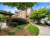 Beautifully landscaped condo exterior featuring brick facade, a pathway, and lush green trees at 1735 Peachtree Ne St # 316, Atlanta, GA 30309