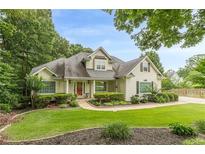 Charming home with a manicured lawn, lush landscaping, and a welcoming red front door at 9707 Squirrel Wood Run, Douglasville, GA 30135