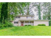 Charming two-story home with a covered front porch and mature trees at 4715 Wildginger Run, Lithonia, GA 30038