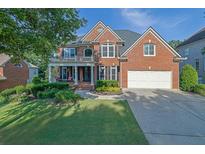 Charming two-story brick home with a manicured lawn, lush landscaping, and a two-car garage at 6260 Sturbridge Ln, Cumming, GA 30040