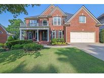 Beautiful two-story brick home featuring a covered front porch and manicured landscaping at 6260 Sturbridge Ln, Cumming, GA 30040