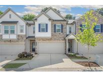 Charming townhome featuring a stone and siding exterior, attached garage, and well-manicured landscaping at 1363 Cooper Springs Rd, Grayson, GA 30017