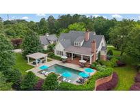 Aerial view of a backyard oasis with a sparkling pool, lounge chairs, and covered patio perfect for entertaining at 710 Cox Rd, Roswell, GA 30075