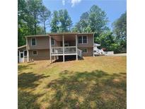 Back exterior view featuring a large yard and elevated porch with white railings at 976 Bakers Bridge Rd, Douglasville, GA 30134