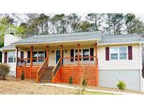 Charming ranch-style home featuring a spacious front porch with wooden deck and beige siding at 112 Village Ct, Woodstock, GA 30188