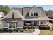 Charming two-story home featuring stone accents, gray siding, a cozy porch swing, and manicured landscaping at 220 Alcovy Reserve Way, Covington, GA 30014