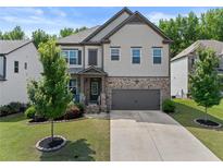 Charming two-story home features a stone and shingle facade, well-manicured lawn, and an attached two-car garage at 4568 Mantova Dr, Buford, GA 30519