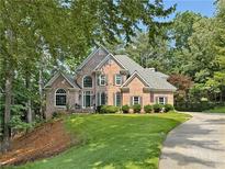 Beautiful two-story brick home with manicured lawn and mature trees at 120 Forest Breeze Cv, Alpharetta, GA 30022