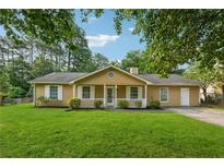 Inviting one-story home featuring a manicured lawn, classic shutters, front porch, and mature landscaping at 3690 Basswood Rd, Snellville, GA 30039