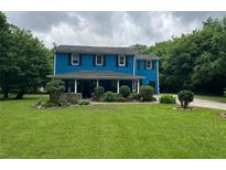Charming two-story home with a lush green lawn and mature trees under a cloudy sky at 5560 Old Bill Cook Rd, College Park, GA 30349