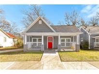 Charming gray home featuring a welcoming front porch with a red door and manicured lawn at 1091 Longley Nw Ave, Atlanta, GA 30318