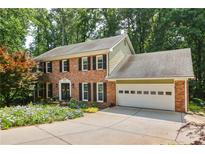Charming two-story brick home featuring a two-car garage and a beautifully landscaped front yard with vibrant flowers at 3453 Drayton Ne Dr, Roswell, GA 30075