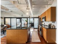 Modern kitchen features wooden cabinets, granite countertops, stainless steel appliances, and industrial-style ceiling at 878 Peachtree Ne St # 704, Atlanta, GA 30309