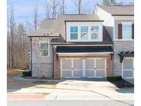 Charming townhouse showcasing a two-car garage and stone and siding accents for stylish curb appeal at 185 Bellehaven Dr, Woodstock, GA 30188