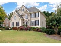 Charming two-story home featuring a stone facade and a well-manicured lawn and colorful, mature landscaping at 4651 Oakleigh Manor Dr, Powder Springs, GA 30127