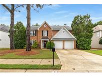 Charming two-story brick home features a manicured front yard, mature trees, and a two-car garage at 1355 Pinebreeze Way, Marietta, GA 30062