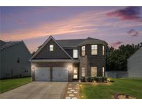 Charming two-story home with a two-car garage, brick facade, manicured lawn, and beautiful twilight sky at 210 Kestrel Cir, Covington, GA 30014