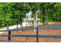 Charming single-story home with a long driveway and a well-maintained, landscaped front yard and black country fence at 1960 York Dr, Canton, GA 30114