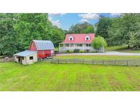 Charming farmhouse with red roof, barn, sprawling yard, and fenced perimeter at 1365 Lower Creighton Rd, Cumming, GA 30028