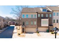 New brick townhome featuring a two-car garage, well-maintained lawn and traditional architectural details at 1110 Bakary Ct, Decatur, GA 30032