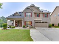 Charming two-story home with brick and siding, a well-manicured lawn, and solar panels on the roof at 893 Whitfield Oak Rd, Auburn, GA 30011